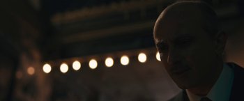 Movie still from “Wormwood” (2017), directed by Errol Morris – A man with a bald head is standing in front of lights; Close Up shot, Low angle