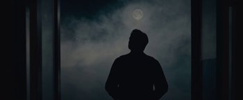 Movie still from “Wormwood” (2017), directed by Errol Morris – A man standing in front of the moon in the night sky; Medium shot, Low angle