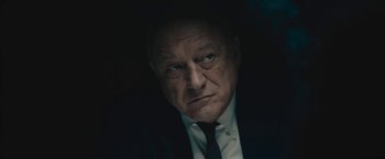 Movie still from “Wormwood” (2017), directed by Errol Morris – An older man wearing a suit and tie in the dark; Close Up shot, Low angle