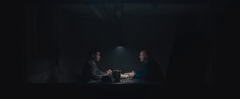 Movie still from “Wormwood” (2017), directed by Errol Morris – Two men sitting at a table in a dark room; Wide shot, Over the shoulder angle