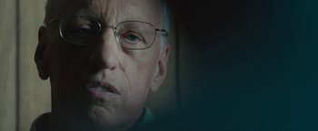 Movie still from “Wormwood” (2017), directed by Errol Morris – An older man wearing glasses looking at the camera; Close Up shot, Over the shoulder angle
