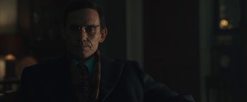Movie still from “Wormwood” (2017), directed by Errol Morris – A man in a suit and tie wearing glasses; Close Up shot, Low angle