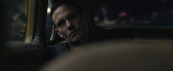 Movie still from “Wormwood” (2017), directed by Errol Morris – A man with glasses sitting in the back seat of a car; Close Up shot, Over the shoulder angle