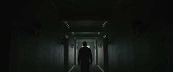 Movie still from “Wormwood” (2017), directed by Errol Morris – A man standing in a dark hallway looking at the light; Wide shot, Low angle