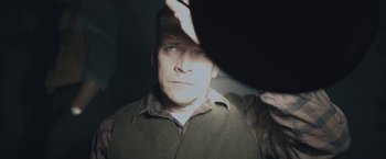 Movie still from “Wormwood” (2017), directed by Errol Morris – A man in a hat and jacket looking at the camera; Close Up shot, High angle