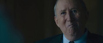 Movie still from “Wormwood” (2017), directed by Errol Morris – An older man wearing a suit and tie; Close Up shot, Over the shoulder angle