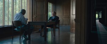 Movie still from “Wormwood” (2017), directed by Errol Morris – A man sitting at a table in front of a window; Wide shot, Over the shoulder angle