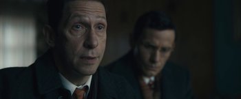 Movie still from “Wormwood” (2017), directed by Errol Morris – A man in a suit and tie next to another man in a suit and tie; Close Up shot, Over the shoulder angle