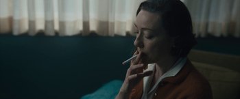 Movie still from “Wormwood” (2017), directed by Errol Morris – A woman smoking a cigarette while sitting on a couch; Close Up shot, Over the shoulder angle