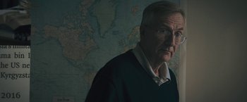Movie still from “Wormwood” (2017), directed by Errol Morris – An older man standing in front of a world map; Close Up shot, Low angle