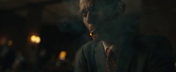 Movie still from “Wormwood” (2017), directed by Errol Morris – An older man in a suit smoking a cigarette; Close Up shot, Over the shoulder angle