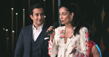 Movie still from “Yeh Ballet” (2020), directed by Sooni Taraporevala – A man and a woman standing next to each other holding microphones; Medium shot, Over the shoulder angle
