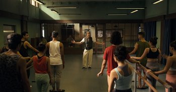 Movie still from “Yeh Ballet” (2020), directed by Sooni Taraporevala – A group of people standing around in a room; Wide shot, Over the shoulder angle
