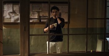 Movie still from “Yeh Ballet” (2020), directed by Sooni Taraporevala – A man standing in front of a window holding a coffee cup; Medium shot, Low angle