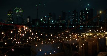Movie still from “Yeh Ballet” (2020), directed by Sooni Taraporevala – A string of lights hanging over a city at night; Extreme Wide shot, High angle