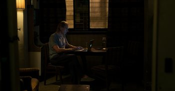 Movie still from “Yeh Ballet” (2020), directed by Sooni Taraporevala – A man sitting at a table using a laptop computer; Wide shot, High angle