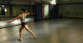 Movie still from “Yeh Ballet” (2020), directed by Sooni Taraporevala – A man in shorts and a tank top is holding a wooden stick; Wide shot, Low angle