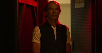Movie still from “Yeh Ballet” (2020), directed by Sooni Taraporevala – A man with long hair standing in front of a red wall; Close Up shot, Low angle