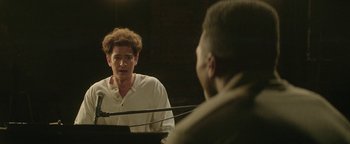 Movie still from “tick, tick... BOOM!” (2021), directed by Lin-Manuel Miranda – A man sitting in front of another man in front of a grand piano; Close Up shot, Over the shoulder angle
