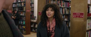 Movie still from “tick, tick... BOOM!” (2021), directed by Lin-Manuel Miranda – A young woman with curly black hair wearing a jacket and a pink scarf; Close Up shot, Over the shoulder angle
