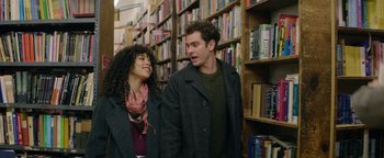 Movie still from “tick, tick... BOOM!” (2021), directed by Lin-Manuel Miranda – A man and a woman standing next to each other in front of a book shelf; Medium shot, Over the shoulder angle