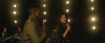 Movie still from “tick, tick... BOOM!” (2021), directed by Lin-Manuel Miranda – A man and a woman holding microphones in a room; Medium shot, Over the shoulder angle