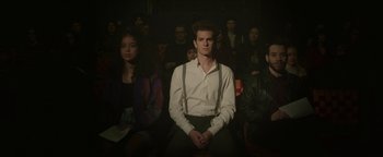 Movie still from “tick, tick... BOOM!” (2021), directed by Lin-Manuel Miranda – A man sitting in front of a group of people; Medium shot, High angle
