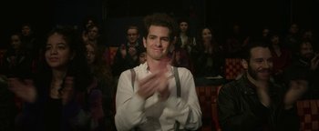 Movie still from “tick, tick... BOOM!” (2021), directed by Lin-Manuel Miranda – A man clapping in front of a group of people; Medium shot, Over the shoulder angle