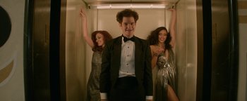 Movie still from “tick, tick... BOOM!” (2021), directed by Lin-Manuel Miranda – A man in a tuxedo standing between two women in dresses; Medium shot, Low angle