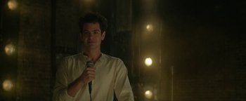 Movie still from “tick, tick... BOOM!” (2021), directed by Lin-Manuel Miranda – A man holding a microphone while standing in front of a crowd; Medium shot, Over the shoulder angle