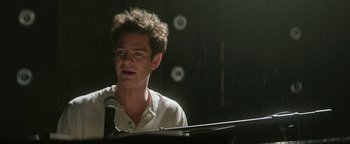 Movie still from “tick, tick... BOOM!” (2021), directed by Lin-Manuel Miranda – A man with curly hair and a white shirt standing at a microphone; Close Up shot, Over the shoulder angle