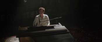 Movie still from “tick, tick... BOOM!” (2021), directed by Lin-Manuel Miranda – A man standing at a podium with a microphone; Medium shot, High angle