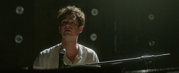 Movie still from “tick, tick... BOOM!” (2021), directed by Lin-Manuel Miranda – A man standing in front of a microphone in a dark room; Close Up shot, Low angle