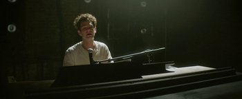 Movie still from “tick, tick... BOOM!” (2021), directed by Lin-Manuel Miranda – A man sitting in front of a microphone at a piano; Medium shot, Over the shoulder angle