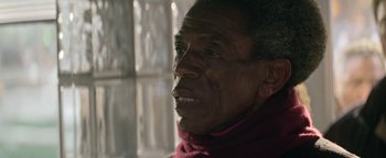 Movie still from “tick, tick... BOOM!” (2021), directed by Lin-Manuel Miranda – An older man wearing a red scarf looking at the camera; Close Up shot, Over the shoulder angle