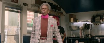 Movie still from “tick, tick... BOOM!” (2021), directed by Lin-Manuel Miranda – An older man in a plaid jacket and a pink scarf; Medium shot, Over the shoulder angle