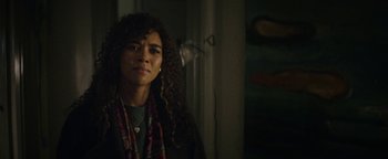 Movie still from “tick, tick... BOOM!” (2021), directed by Lin-Manuel Miranda – A woman with curly brown hair wearing a scarf; Close Up shot, Over the shoulder angle
