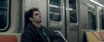 Movie still from “tick, tick... BOOM!” (2021), directed by Lin-Manuel Miranda – A man sitting on a subway train with his head resting on his arm; Close Up shot, Low angle