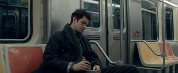 Movie still from “tick, tick... BOOM!” (2021), directed by Lin-Manuel Miranda – A man sitting on a train looking at his cell phone; Close Up shot, High angle