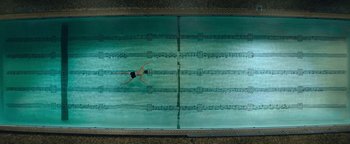 Movie still from “tick, tick... BOOM!” (2021), directed by Lin-Manuel Miranda – An overhead view of a person swimming in a pool; Extreme Wide shot, Overhead angle