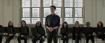 Movie still from “tick, tick... BOOM!” (2021), directed by Lin-Manuel Miranda – A man standing in front of a group of people; Wide shot, Over the shoulder angle