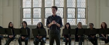 Movie still from “tick, tick... BOOM!” (2021), directed by Lin-Manuel Miranda – A man standing in front of a group of people; Wide shot, Over the shoulder angle