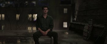 Movie still from “tick, tick... BOOM!” (2021), directed by Lin-Manuel Miranda – A man sitting on top of a chair in a dark room; Wide shot, High angle