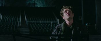 Movie still from “tick, tick... BOOM!” (2021), directed by Lin-Manuel Miranda – A man sitting in front of a piano in a dark room; Close Up shot, Low angle