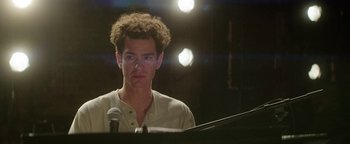 Movie still from “tick, tick... BOOM!” (2021), directed by Lin-Manuel Miranda – A man sitting in front of a microphone in front of a piano; Close Up shot, Low angle