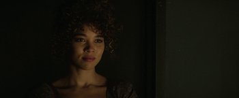 Movie still from “tick, tick... BOOM!” (2021), directed by Lin-Manuel Miranda – A woman with curly brown hair is posing for the camera; Close Up shot, Over the shoulder angle