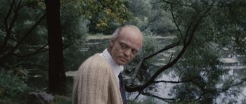 Movie still from “Solaris” (1972), directed by Andrei Tarkovsky – An older man wearing a sweater and a tie in a wooded area; Close Up shot, Over the shoulder angle