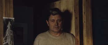 Movie still from “Solaris” (1972), directed by Andrei Tarkovsky – A man in a tan shirt standing next to a wooden wall; Close Up shot, High angle