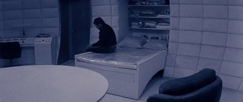 Movie still from “Solaris” (1972), directed by Andrei Tarkovsky – A man sitting on top of a bed in a room; Wide shot, High angle