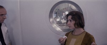 Movie still from “Solaris” (1972), directed by Andrei Tarkovsky – A woman is holding a piece of paper in front of a round window; Medium shot, Over the shoulder angle